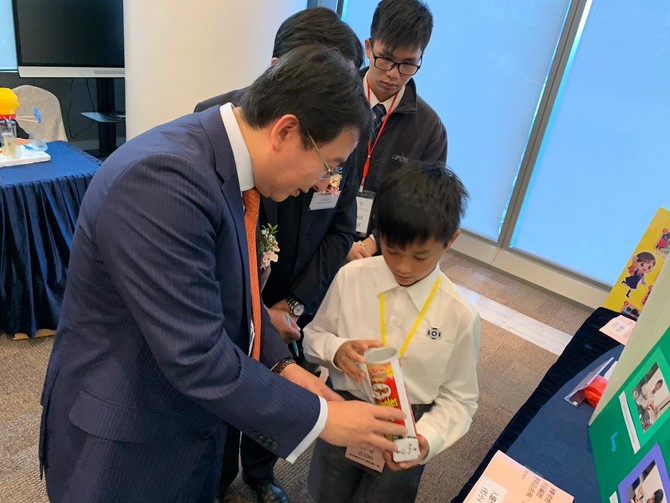 香港小学生向仁济医院董事局主席冯卓能先生示范如何操作发明品