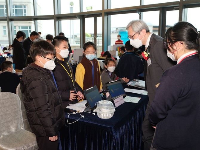 學生向總評評審團主席香港城市大學李兆基教授(電子學習)葉豪盛教授MH介紹發明作品的設計慨念及用途