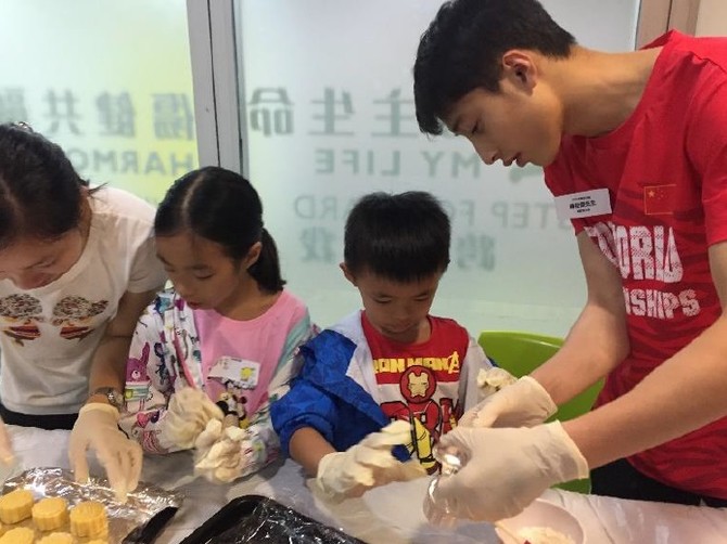 國家跳水隊成員與一起參與的沙田青年服務團團員和香港傷健協會賽馬會沙田青少年綜合服務中心的小朋友一起製作月餅。